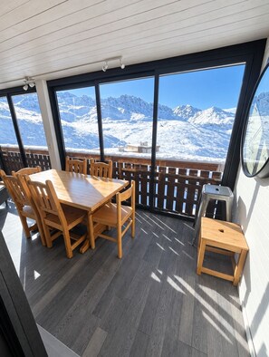 A wooden dining table with chairs, a small stool, and a window with a view of snow-covered mountains. - Val Thorens - Ski In/Out - 7 Beds Flat (S-K10) (Val Thorens)