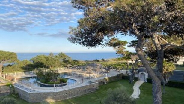 Una propiedad costera con piscina de piedra, senderos y vistas al mar.