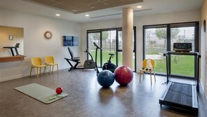 A modern gym with exercise equipment, a yoga mat, and a treadmill.