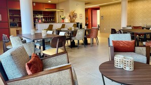 A modern dining area with round tables and chairs, a bar area with shelves, and a salon sign.