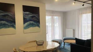 Una sala de estar con una mesa redonda, sillas, un sofá y dos cuadros en la pared.
