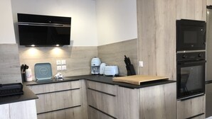 Una cocina moderna con armarios de madera, encimera negra, horno empotrado y microondas.