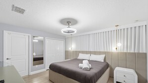 Un dormitorio moderno con una cama grande, mesitas de noche, un armario y un espejo.