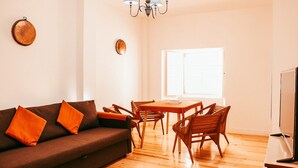 A modern living room with a brown sofa, wooden dining table, and chairs. - Beautiful apartment in Lisboa with terrace (Lisboa ciudad)