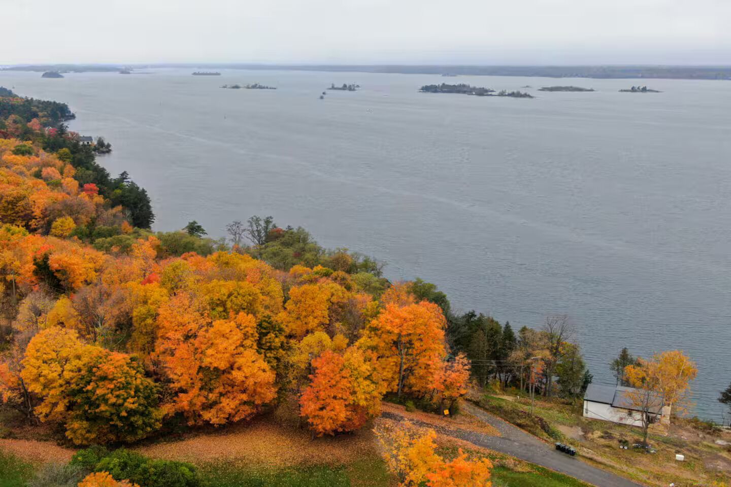 A coastal landscape with autumn foliage, a body of water, and distant islands.