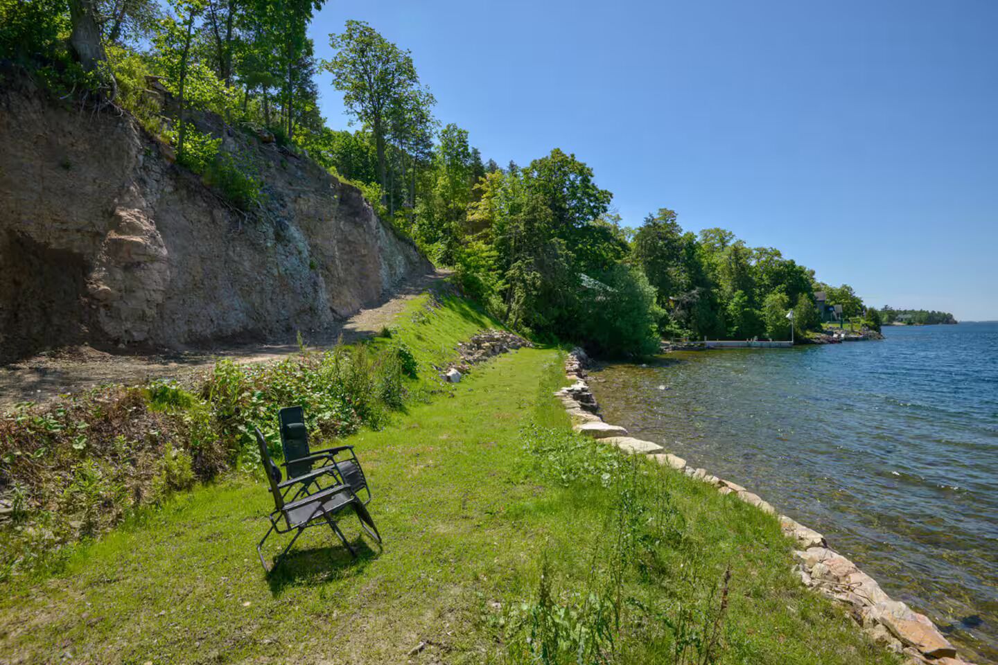 Una panchina sul lago, vicino a una scogliera rocciosa e con acque calme.