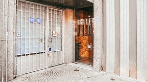 Una entrada protegida con un portón metálico y un muro de azulejos.