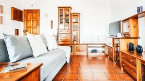 Olohuone, jossa on sohva, puukaappeja ja televisio.