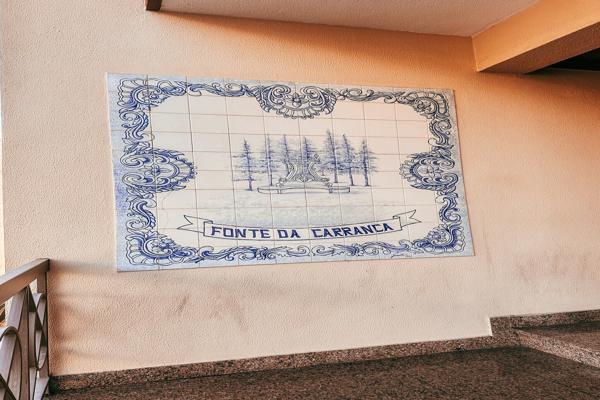 A tiled wall with a decorative border and a central illustration of a fountain with trees.
