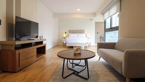 A modern hotel room with a bed, a TV on a wooden console, a round coffee table, and a sofa. - w* | Engaging Loft in the Heart of San Isidro (San Isidro)