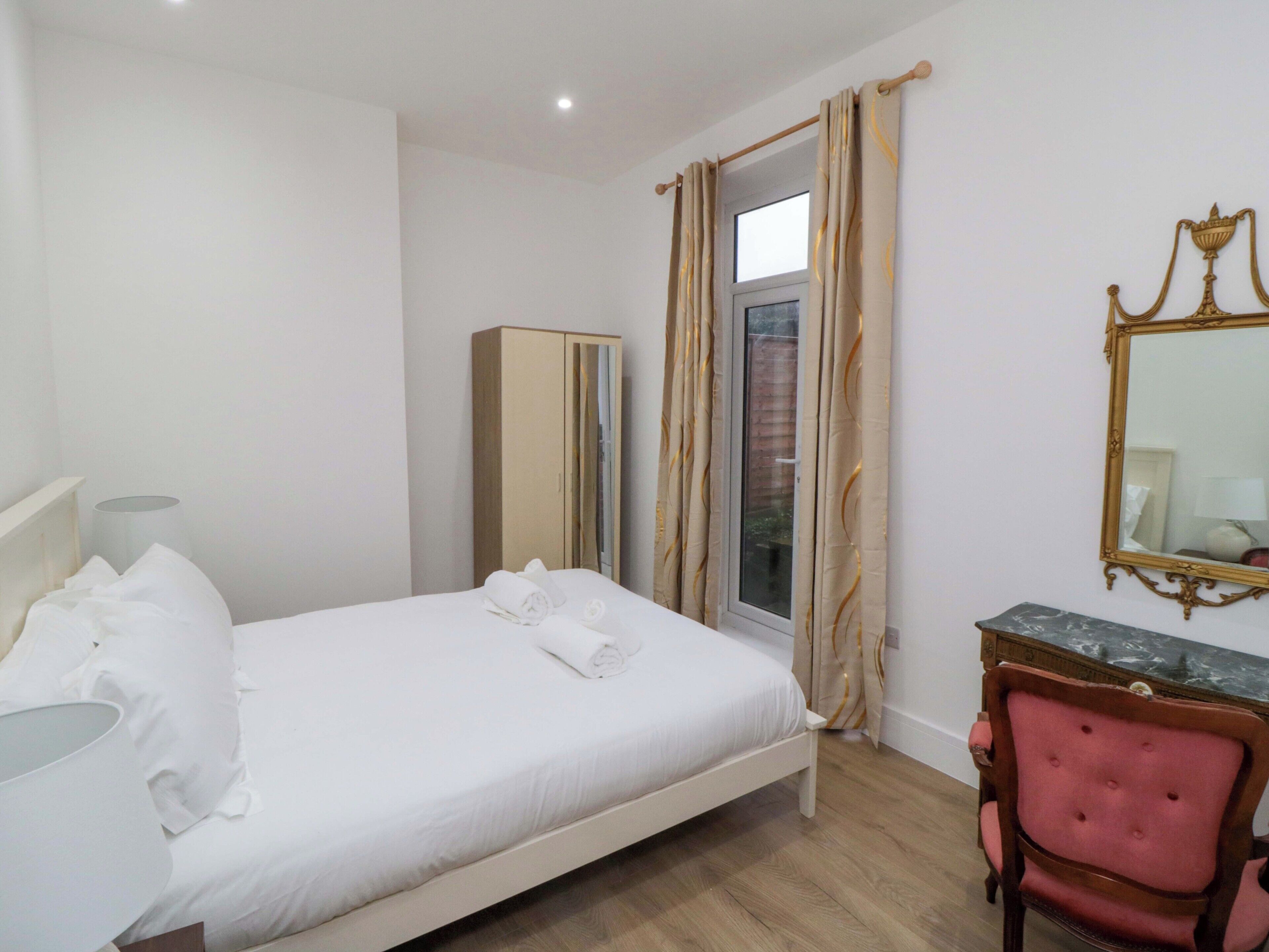 Ein Hotelzimmer mit Bett, Kleiderschrank, Schreibtisch mit Stuhl und Spiegel an der Wand.