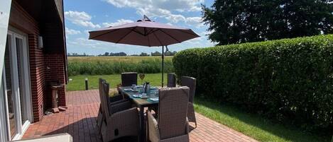 An outdoor patio with a brick floor, a table with chairs, and an umbrella.