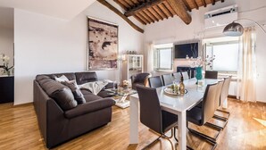 Una sala de estar moderna con techo de madera, un comedor con mesa de vidrio y un cuadro grande en la pared.