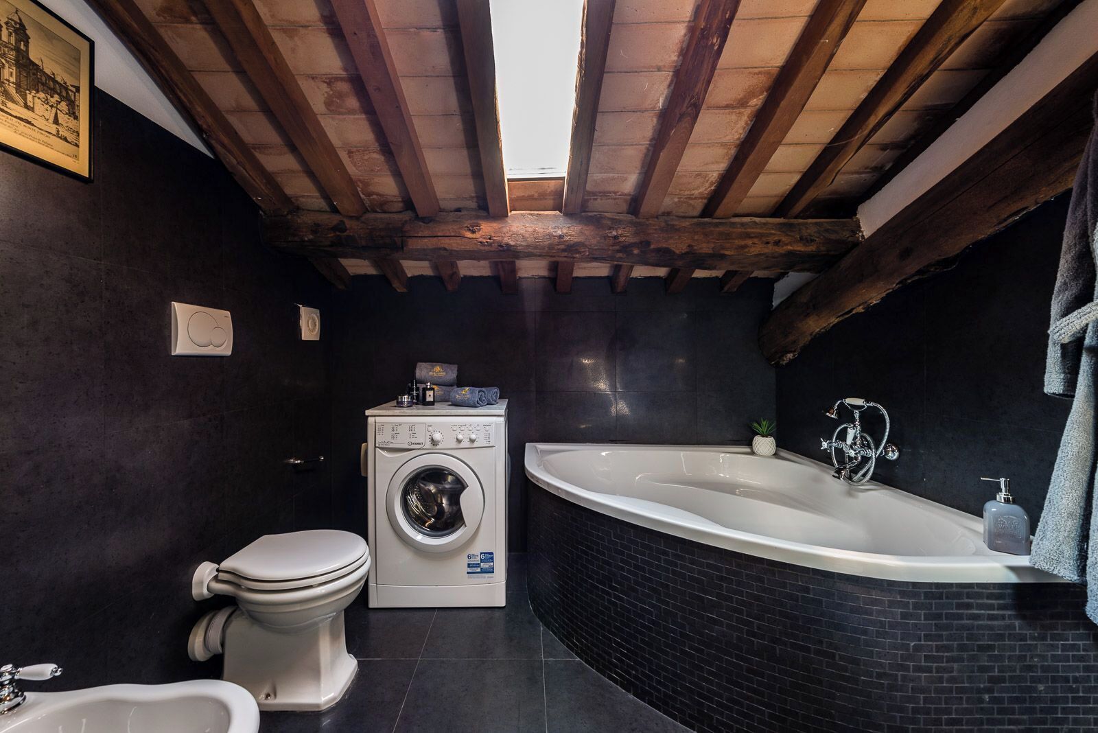 Ein kleines Badezimmer mit Waschmaschine, Toilette und einer großen Badewanne.