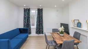 Ein modernes Wohnzimmer mit einem blauen Sofa, einem Holzesstisch und grauen Stühlen.