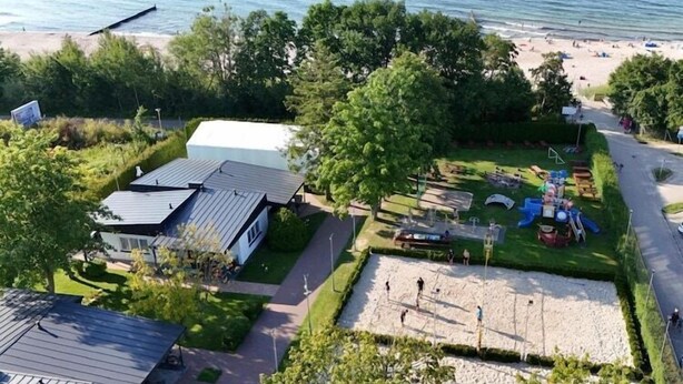 A residential area with a beach, a playground, and a white building with a metal roof. - Comfortable holiday homes, right by the beach (Sianozety)