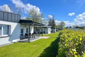 Une rangée de bâtiments modernes, blancs, dotés de toits plats et de grandes fenêtres, qui font probablement partie d’un hôtel ou d’un complexe touristique.