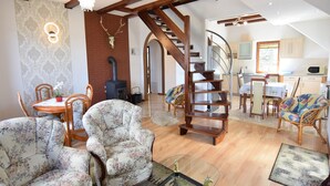 Un vaste salon agrémenté d’un escalier en bois, d’un coin repas et d’une cuisine.