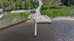 Une propriété au bord du lac, comprenant un quai, une maison et un petit abri de jardin.