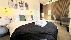 A modern bedroom with a bed, bedside table, and a desk with a chair. - Apartment No.3 @Worcester House & Free Parking (Worcester)