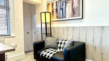 Een moderne woonkamer met een zwarte leren bank, een geruit plaid en een abstract schilderij op de muur.
