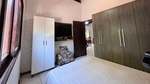Una camera da letto con un letto, un armadio, una televisione a muro e una sedia.