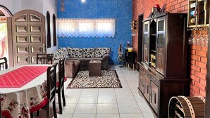 Un accogliente soggiorno con una parete blu strutturata, un mobile in legno con bicchieri da vino e un tappeto decorato.