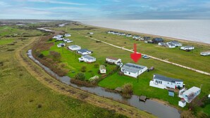 An aerial view of a coastal area with white mobile homes, a river, and a beach.