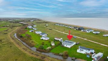An aerial view of a coastal area with white mobile homes, a river, and a beach.