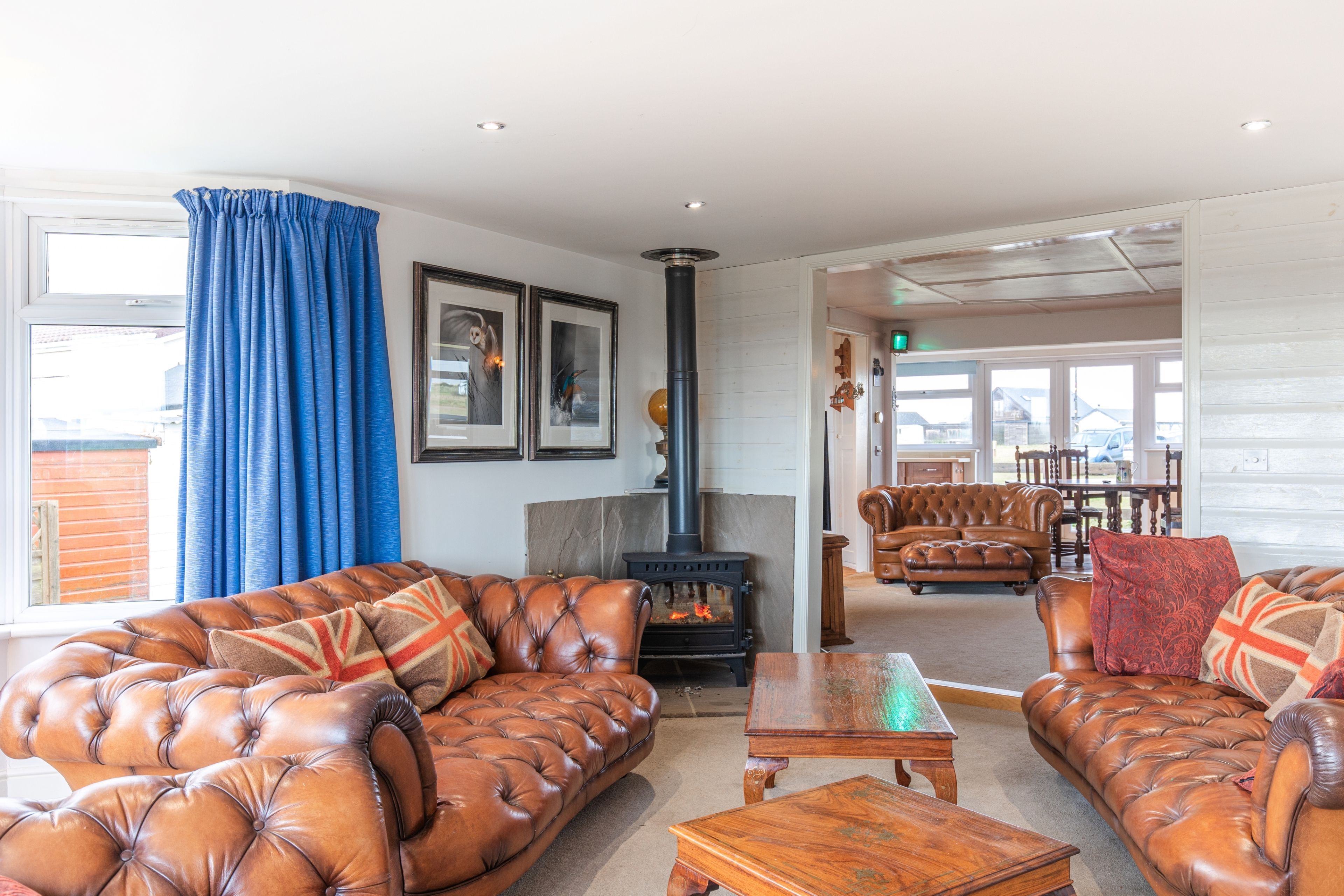 A cozy living room with leather sofas, a fireplace, and a dining area with wooden furniture.