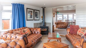 A cozy living room with leather sofas, a fireplace, and a dining area with wooden furniture.