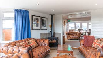 A cozy living room with leather sofas, a fireplace, and a dining area with wooden furniture.