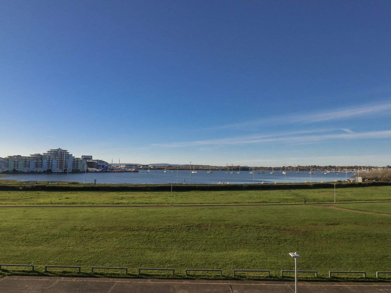 A waterfront view with a grassy area and buildings in the background.