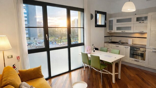 Un apartamento moderno con sofá, mesa de comedor, sillas y zona de cocina.