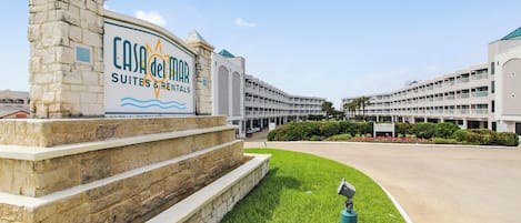 L'ingresso di un hotel con un cartello per 'Casa de Mar Suites & Rentals' e un grande edificio sullo sfondo.