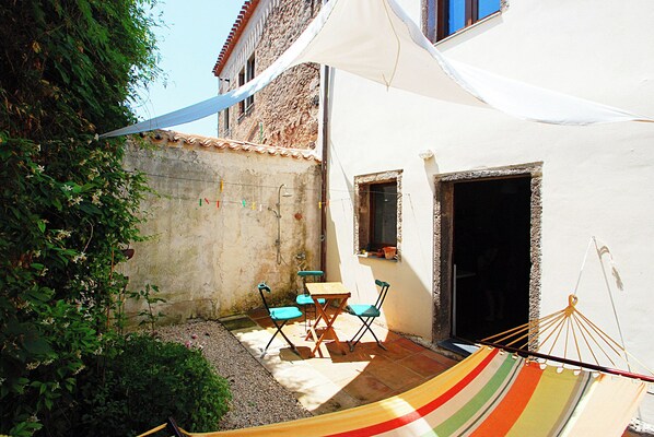 A small patio with a hammock, a table, and chairs.