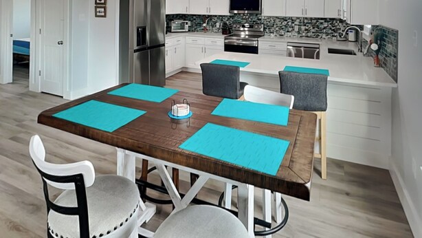 Una cocina moderna con armarios blancos, electrodomésticos de acero inoxidable y una isla central con asientos.