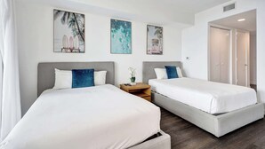 A hotel room with two beds, a small table, and artwork on the wall. - Ocean and Canal View Condo Resort Hallandale 706 (Hallandale Beach)