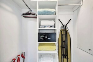 A white closet with shelves containing folded towels, a microwave, and a hanging garment rack. - Ocean and Canal View Condo Resort Hallandale 706 (Hallandale Beach)