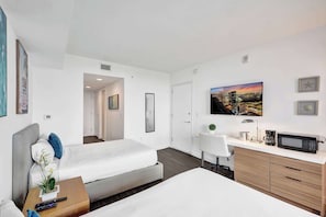 A modern hotel room with a bed, a desk with a computer, a microwave, and a TV. - Ocean and Canal View Condo Resort Hallandale 706 (Hallandale Beach)