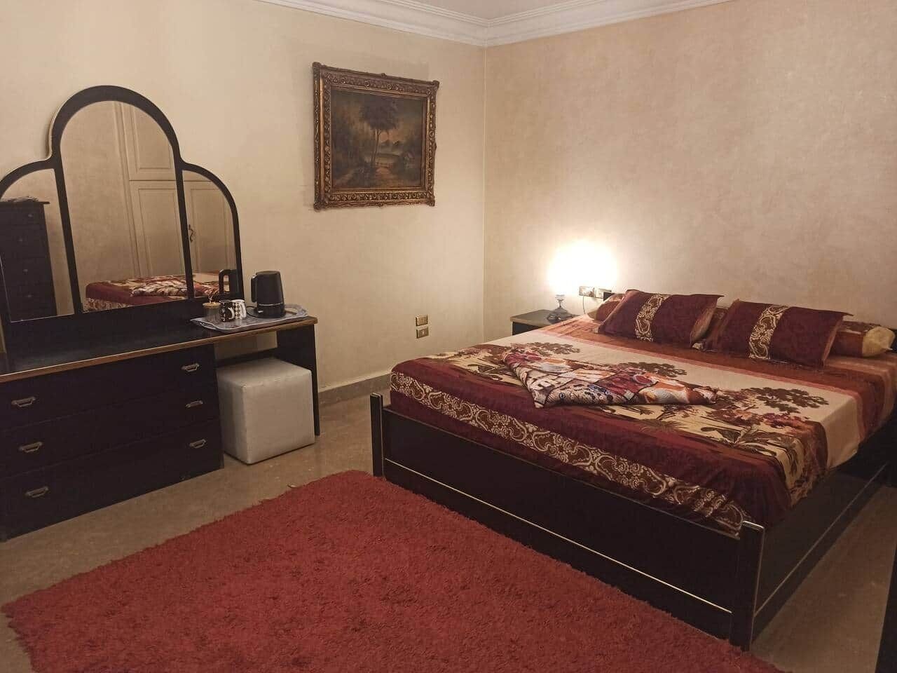 Un dormitorio con cama, cómoda, mesita de noche y espejo.