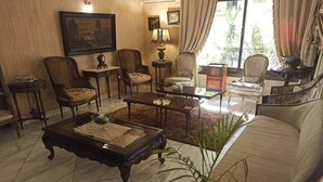 Uma sala de estar tradicional com sofá, poltronas, mesa de centro e abajur.