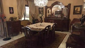 Ein Esszimmer mit rundem Tisch, Stühlen, einer Kandelaber, einem Spiegel und einem Ventilator.