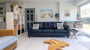 Ein modernes Wohnzimmer mit einem dunkelblauen Sofa, Korbmöbeln und einem Holztisch.