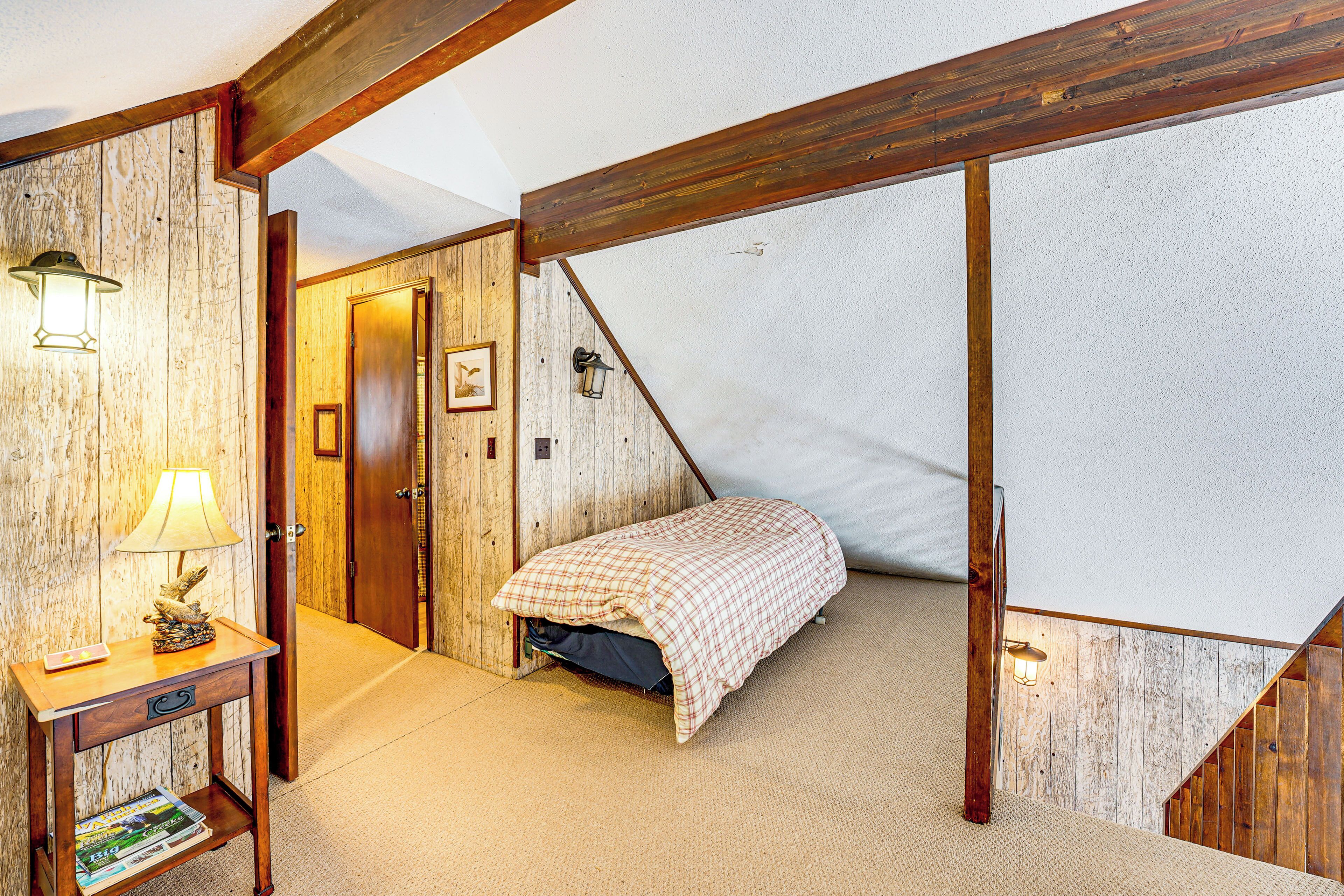 Une chambre à coucher avec un lit, une table de chevet, une lampe et une porte en bois.