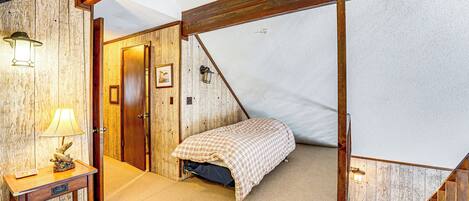 Une chambre à coucher avec un lit, une table de chevet, une lampe et une porte en bois.