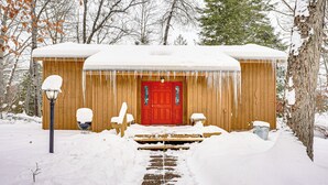 A wooden cabin with a red door, a bench, and a snow-covered path leading to it. - Near Manistee National Forest! Retro Cabin Retreat (Baldwin)