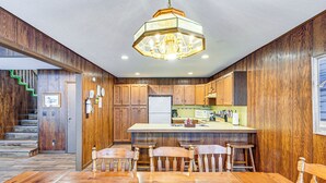 A kitchen with wooden cabinets, a central island, and a chandelier. - Near Manistee National Forest! Retro Cabin Retreat (Baldwin)