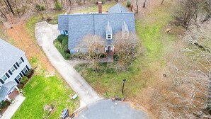 A two-story house with a grey roof, a visible chimney, and a small front yard. - Ballantyne Single-Story Ranch off the Greenway (Charlotte)