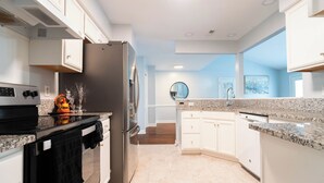 A modern kitchen with white cabinetry, a stainless steel refrigerator, and granite countertops. - Ballantyne Single-Story Ranch off the Greenway (Charlotte)